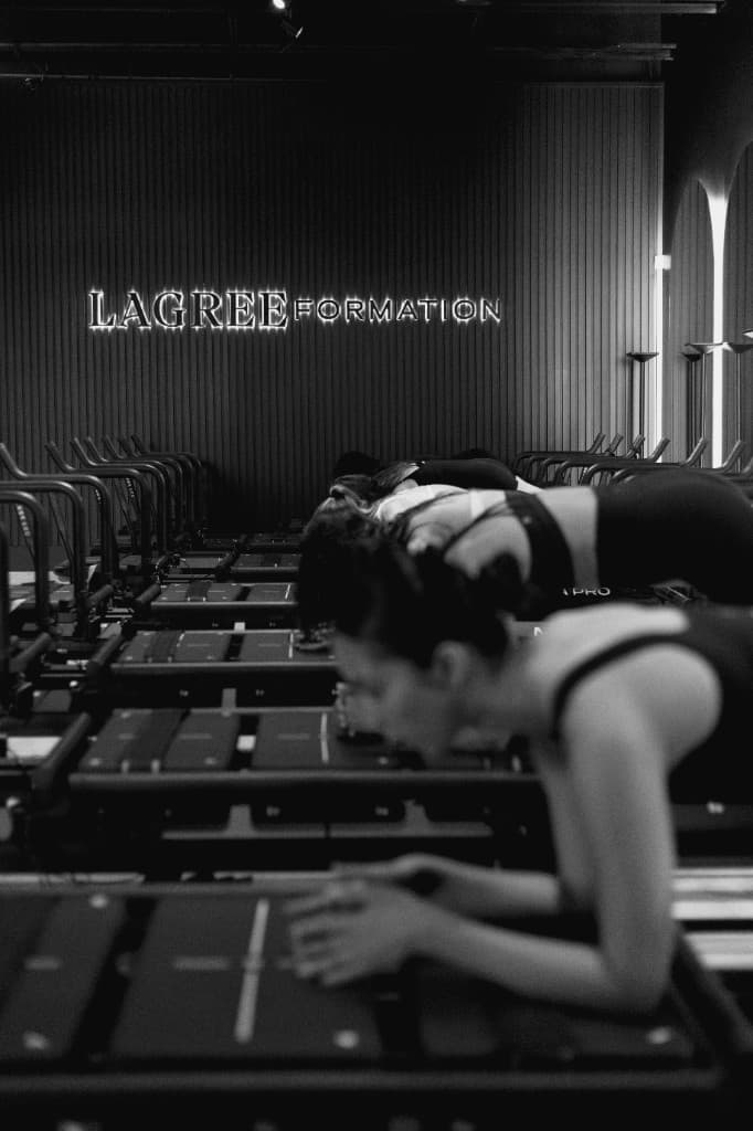 Lagree Formation studio: athletes training on Megaformers in a dramatic black-and-white class.